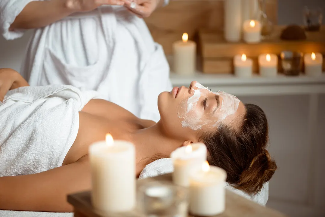 mujer recostada con crema facial en spa